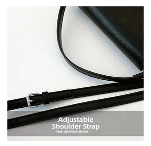 Detail of adjustable black leather shoulder strap with silver buckle on handbag