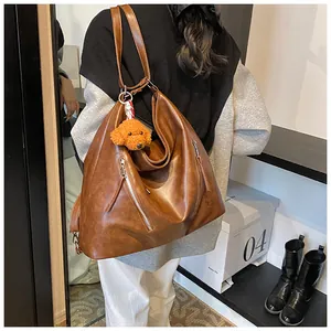 Close-up of vintage brown leather tote bag with metal zippers and cute teddy charm