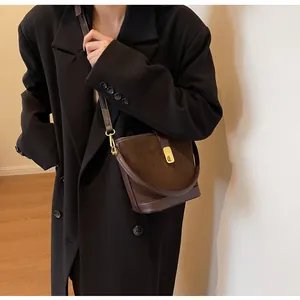 Brown matte bucket bag with gold clasp shown on a model with a black oversized blazer