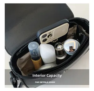 Internal capacity of the black leather saddle bag showing phone and cosmetics