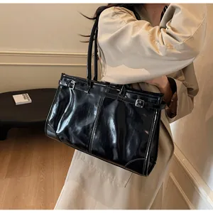 Detail of glossy black leather tote bag with silver buckle and vintage adjustable strap