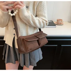Detail of brown faux suede baguette bag featuring front flap pockets and pearl handle