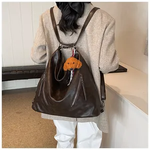 Detail of dark brown faux leather backpack with vertical zippers and plush charm