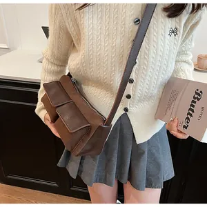 Detail view of brown suede faux leather crossbody bag with dual front flap pockets