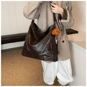 Close-up of vintage brown PU leather shoulder bag with decorative zippers and plush dog charm