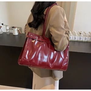 Detail of vintage burgundy glossy leather tote bag with silver buckle and shoulder strap