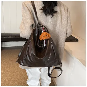 Back view of a large vintage brown faux leather backpack with a cute poodle plush charm