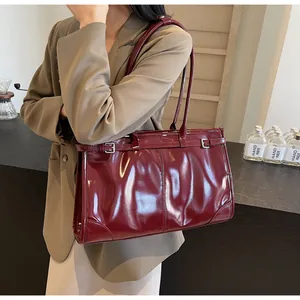 Close-up detail of glossy dark red leather tote bag with silver buckle and long straps