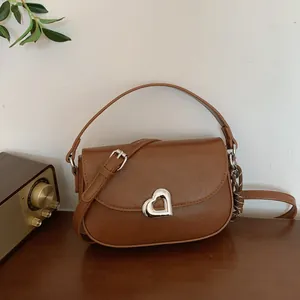 Caramel brown saddle bag with silver heart buckle and adjustable shoulder strap