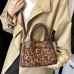Fashionable leopard print handbag with leather trim and gold metal buckle worn with trench coat