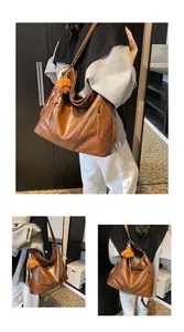Detail of brown faux leather tote bag with metal zipper and plush bear charm accent