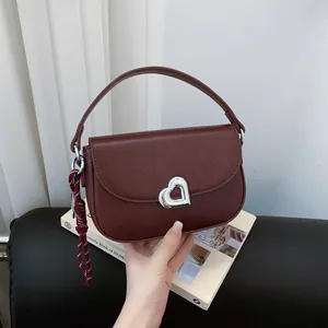 Dark red faux leather saddle bag with silver heart buckle and woven cord charm