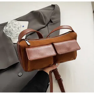 Detailed macro of brown faux suede baguette bag with smooth leather trim and twin pockets