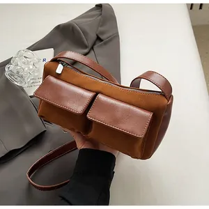 Detailed view of caramel suede baguette bag with twin front pockets and silver hardware