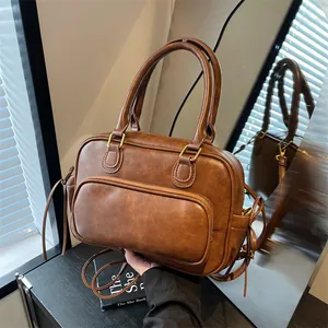 Vintage dark brown bowling handbag with front pocket and round handles on a black surface