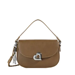 Brown leather saddle bag with silver heart lock and braided strap detail on white background