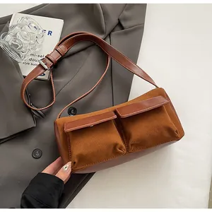 Detail of caramel suede baguette bag with dual front flap pockets and leather straps