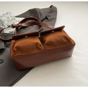 Detailed view of the brown suede and leather baguette bag with dual front utility pockets