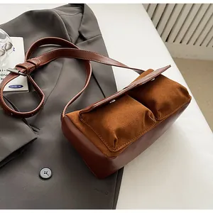 Detail of a brown faux suede crossbody bag featuring a unique double pocket design