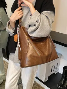 Vintage brown leather tote bag with side zippers, plush ball charm and decorative scarf