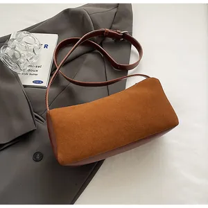 Detail of brown faux suede baguette bag showing the fine texture and adjustable strap