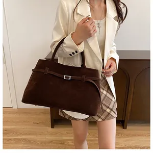 Detail of dark brown matte leather tote bag featuring a decorative silver metal buckle