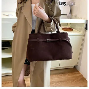 Detail of dark brown matte tote bag with decorative leather strap and silver metal buckle