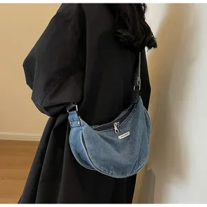Detailed shot of a blue denim hobo bag with adjustable strap worn by a model