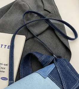 Detail of blue denim shoulder strap with white stitching on a stylish crossbody bag