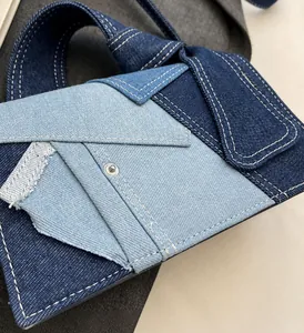 Detail of denim patchwork handbag showing white contrast stitching and metal rivets