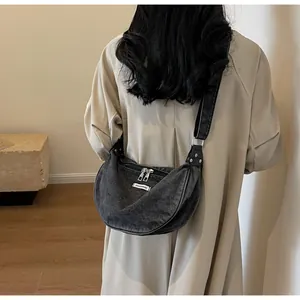 Back view of a washed denim crescent moon bag in dark grey with wide shoulder strap