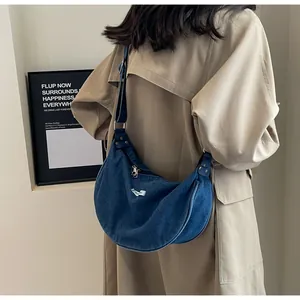 Detail view of deep blue denim hobo bag featuring a white woven fashion label on high quality fabric