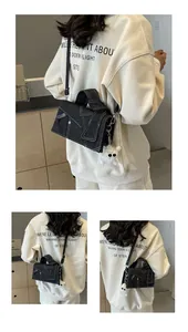 Detailed view of dark blue denim crossbody bag with contrast stitching and bear charm