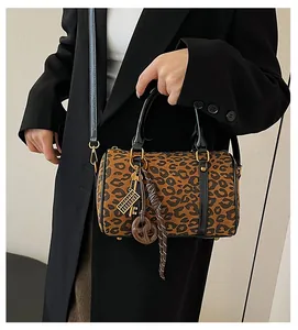 Dettaglio della borsa Boston leopardata con finiture dorate e cinturini in pelle sul modello