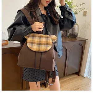 Brauner Cord-Rucksack mit karierter Klappe und Bärenohren, präsentiert am Modell zu Hause