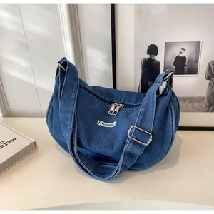 Close-up of vintage blue denim shoulder bag featuring double metal zippers and adjustable strap