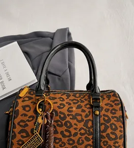 Gros plan du sac Boston léopard avec poignée en cuir noir et détails dorés