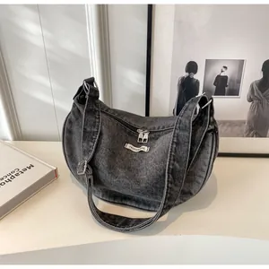 Detail of retro washed denim crescent bag with double zippers and fashion woven label