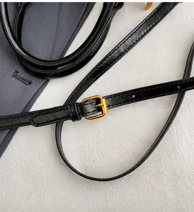 Détail de la bandoulière réglable avec boucle dorée sur un sac en cuir noir brillant