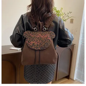 Detail der Bärenklappe mit Leopardenmuster und Kord-Textur auf modischem Rucksack