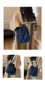 Détail d'un sac seau en jean bleu foncé avec broderie de tulipes et bandoulière réglable