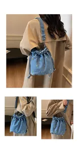 Détail du sac seau en denim bleu avec broderies florales délicates et fermeture à cordon