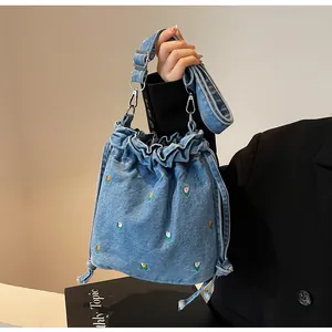 Détail du sac seau en denim bleu avec broderie tulipe et fermeture à cordon réglable