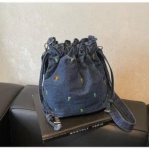 Détail de la broderie de tulipes colorées sur le sac seau en denim avec cordon de serrage