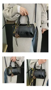 Dettagli di una borsa Boston nera lucida con ciondoli vintage e tracolla sottile