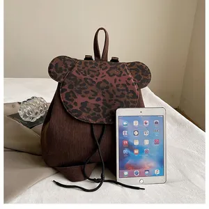 Mini-Damenrucksack mit Leopardenmuster aus Cord, neben einem Tablet zum Größenvergleich