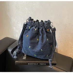 Détail de la broderie de tulipes colorées sur le sac seau en denim bleu foncé à cordon