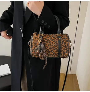 Dettaglio borsa Boston leopardata con ciondolo abaco dorato e manici in pelle nera