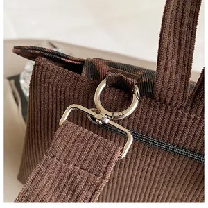 Details von dunkelbrauner Cord-Textur und silbernem Metallverschluss am Rucksack