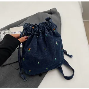 Détail de la broderie florale sur sac seau en denim bleu marine avec cordon de serrage